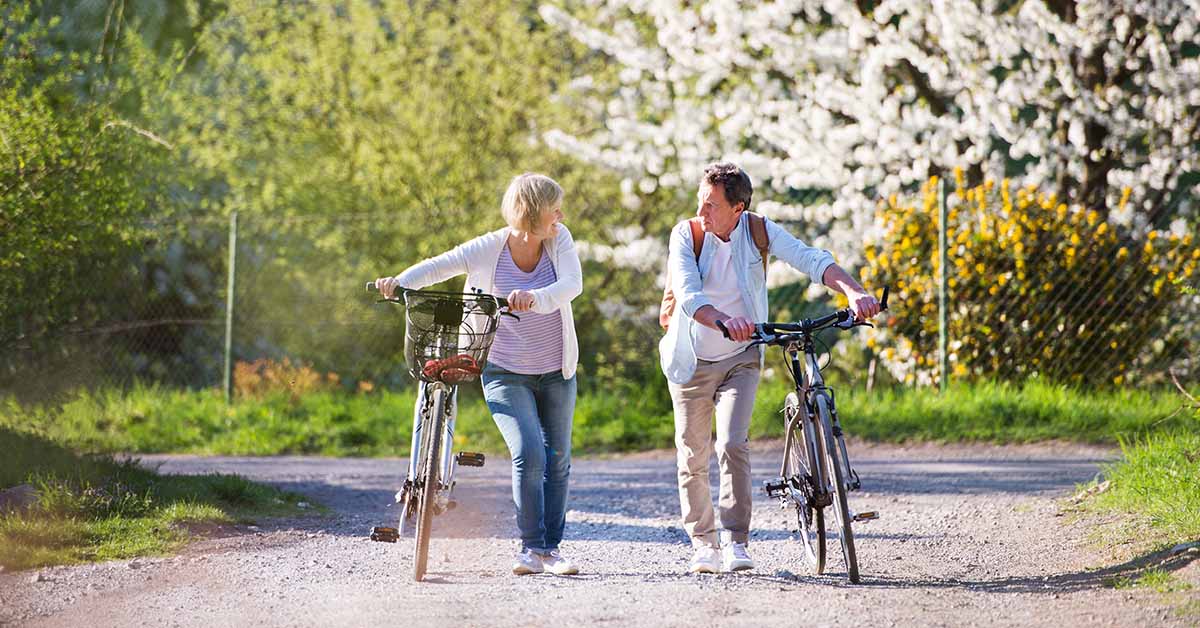 Picture of a man and woman walking along their bikes and speaking to one another.