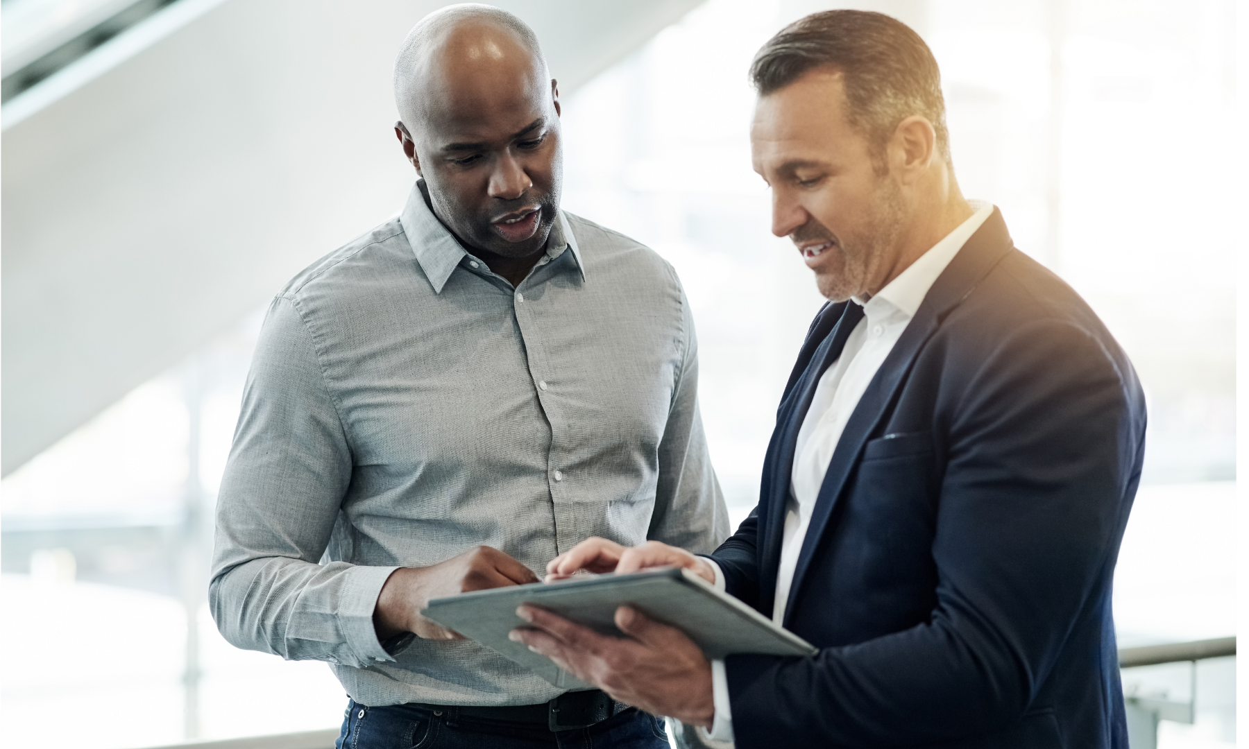 Two men in business clothing looking at a tablet