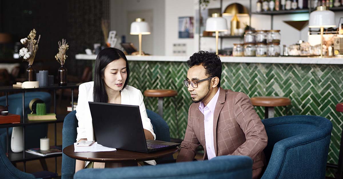 man and woman looking at a laptop at a table at a restaurant