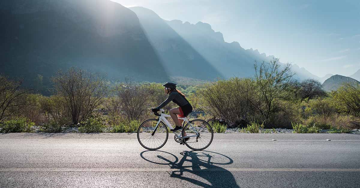 a cyclist riding down an open road