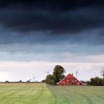 Farmhouse and field under cloudy skies