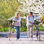 Picture of a man and woman walking along their bikes and speaking to one another.