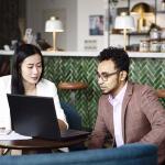 man and woman looking at a laptop at a table at a restaurant